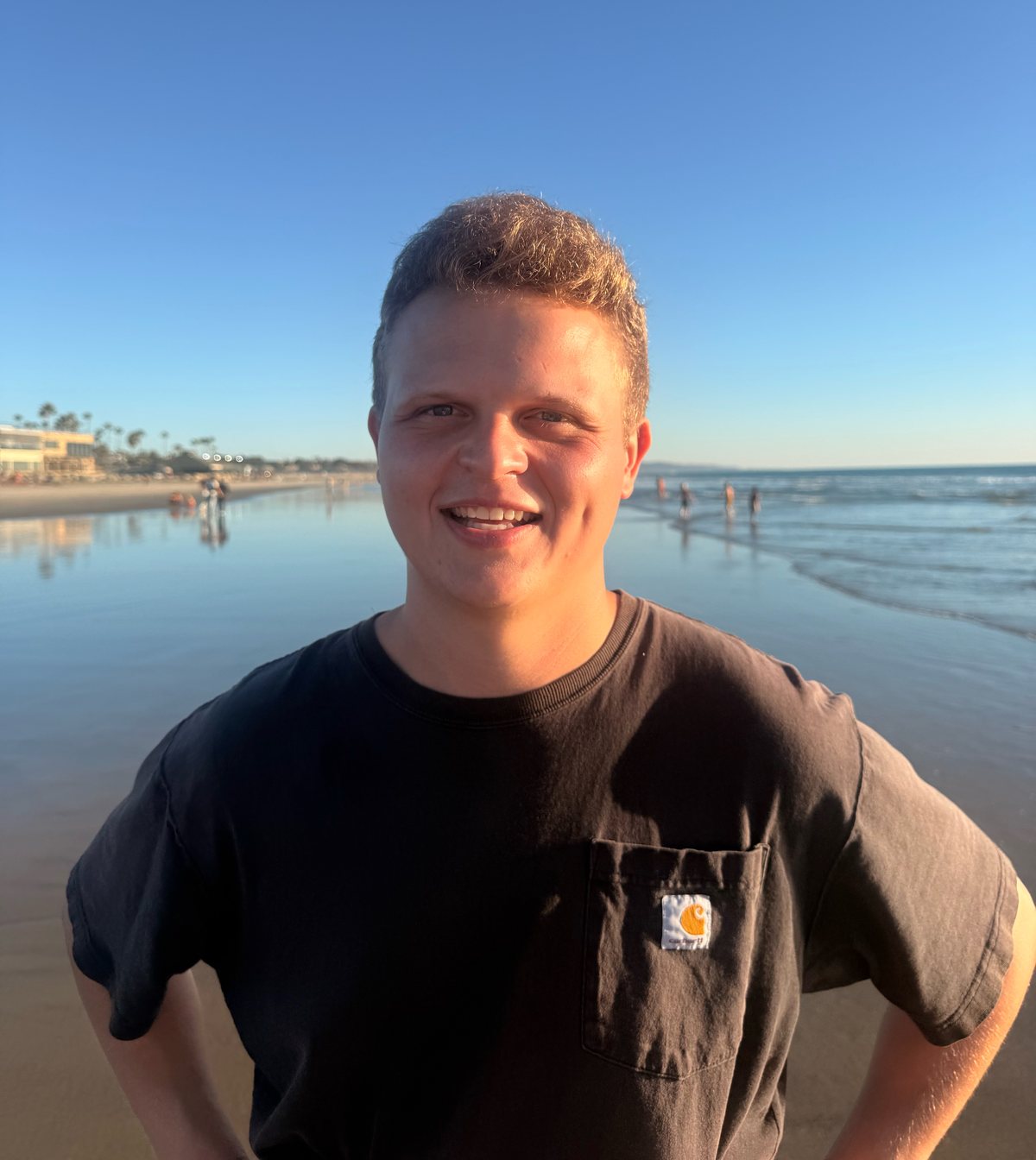 Cole smiling on the beach at sunset, with the ocean behind him